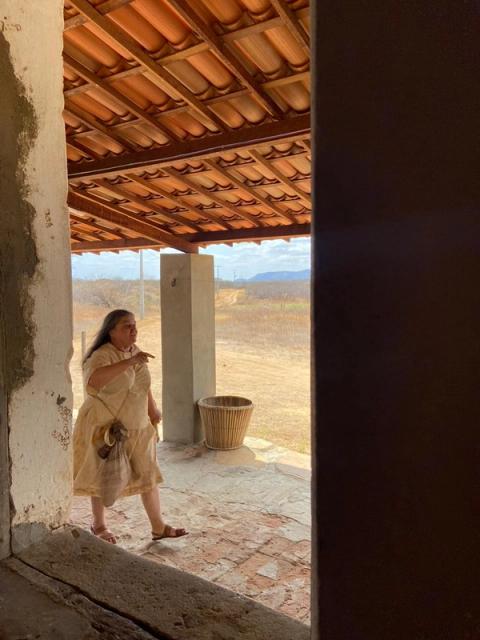 Mulher caminhando em varanda rústica.