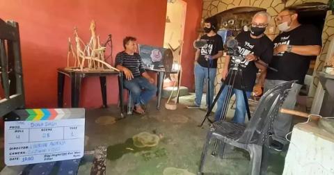 Equipe gravando cena em sala, com clapperboard visível.