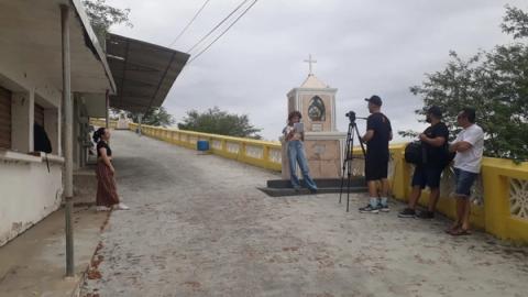 Gravação em ponto com altar ao fundo, equipe filmando.