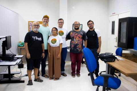 Grupo posando em sala com computadores.