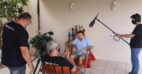 Gravação de entrevista em sala decorada com bonecos.