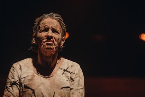 Atriz com rosto coberto de terra, expressando emoção intensa em cena dramática.