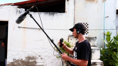 Homem operando microfone profissional ao ar livre, usando fones de ouvido.