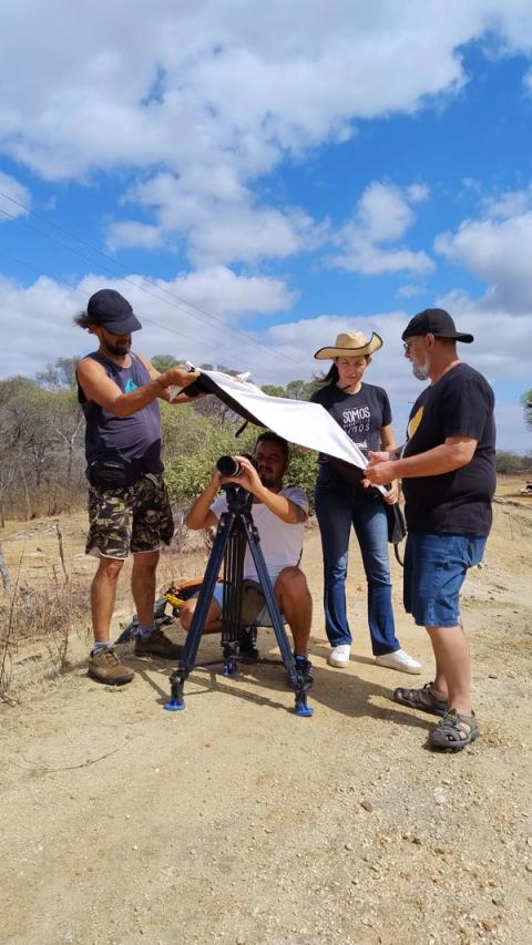 Equipe filmando ao ar livre ajustando equipamentos.