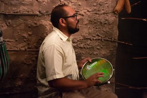 Homem sentado tocando um pandeiro.