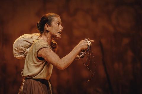 Atriz com maquiagem intensa segurando colar.