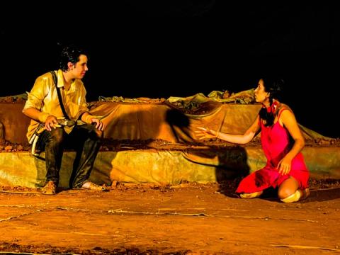 Ator e atriz sentados no chão, conversando.