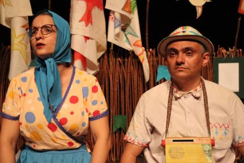 Atriz e ator vestidos tradicionalmente, lado a lado em cena teatral.