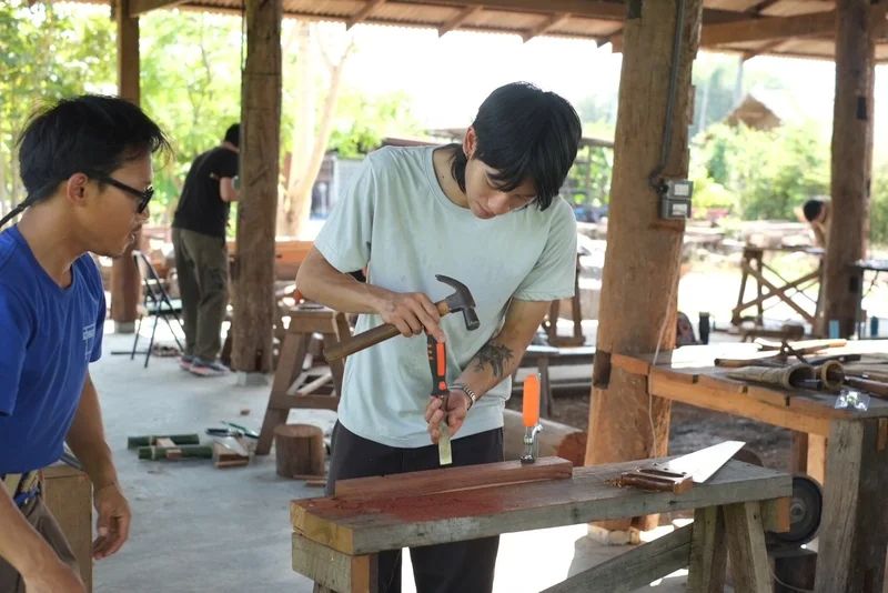 Participants learning to work timber with hand tools at a workbench