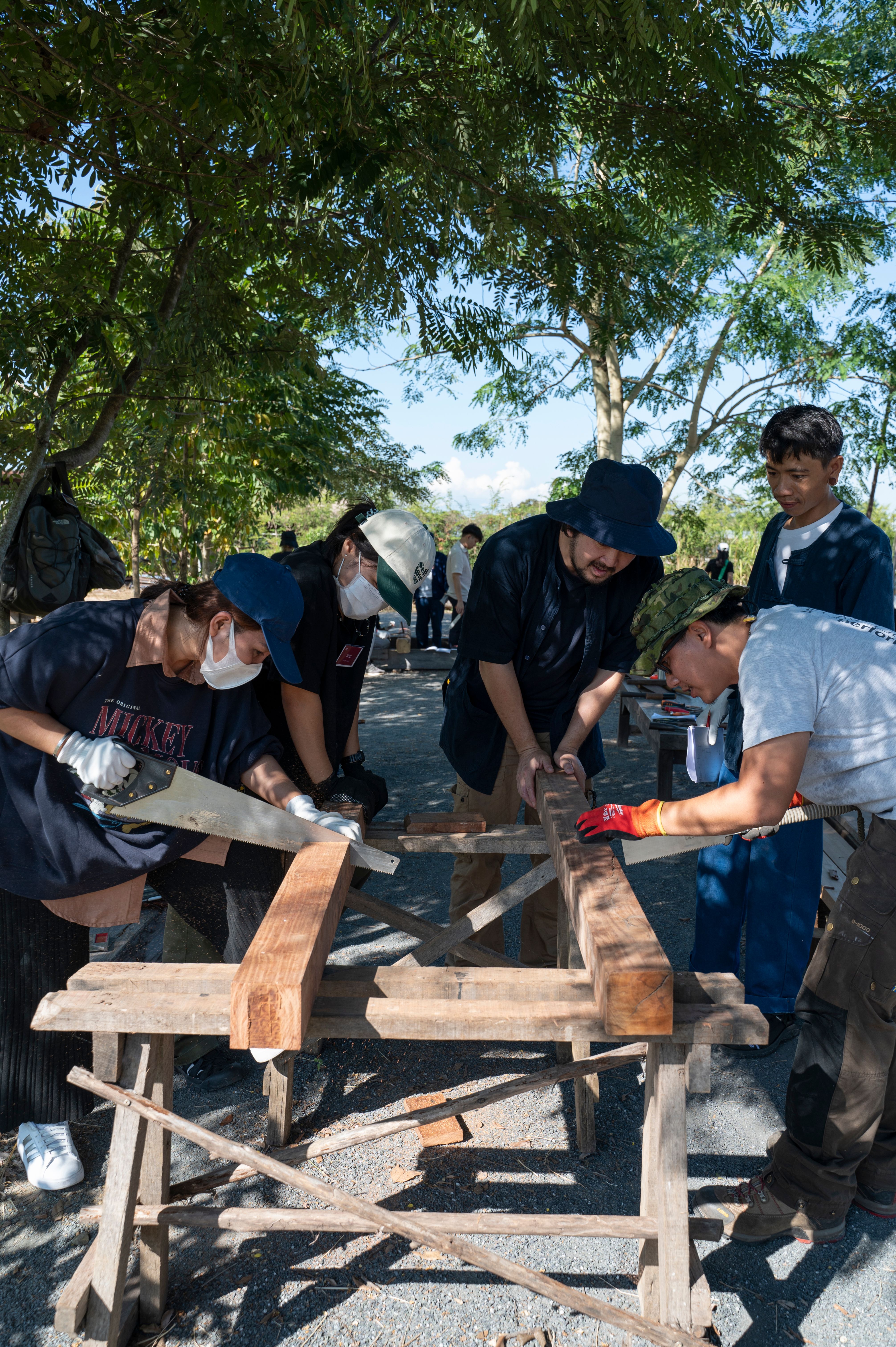 Participants cutting timber together during a Pham workshop