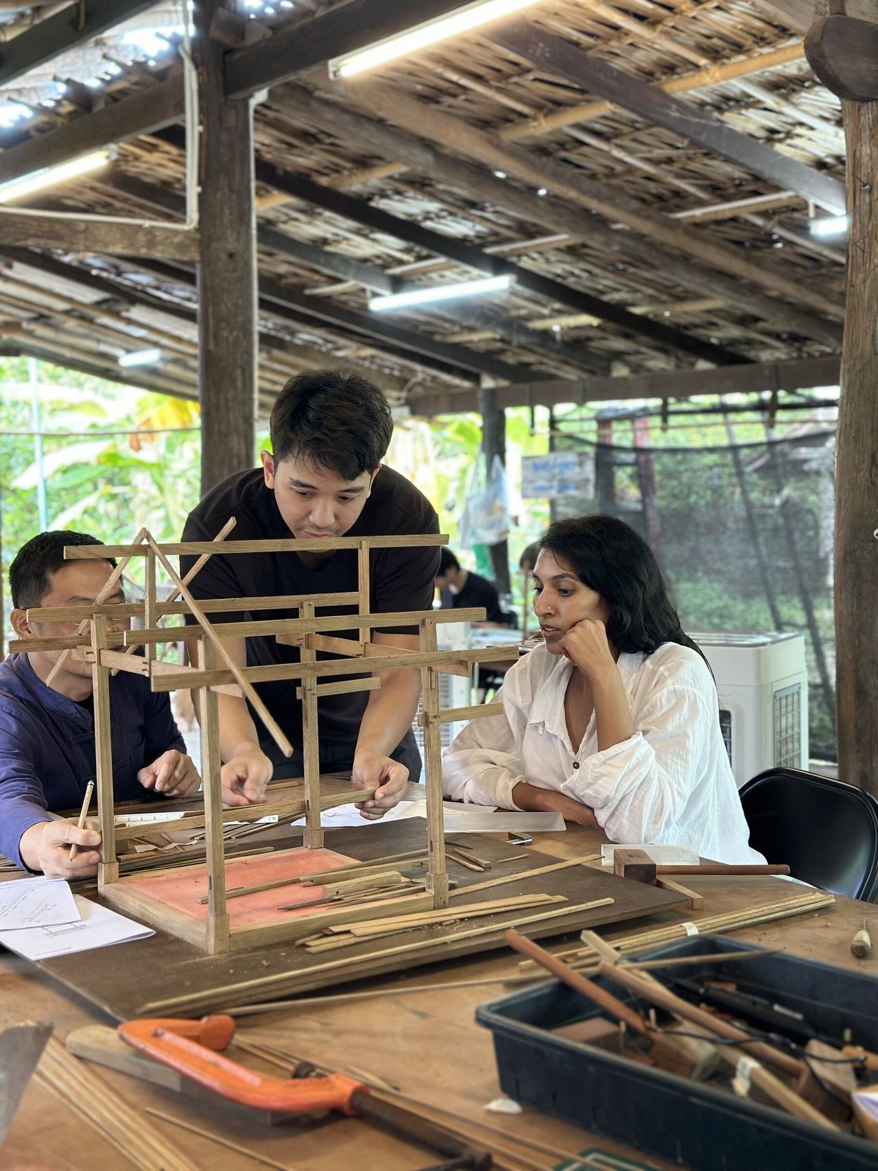 Participants studying a handmade timber pavilion model