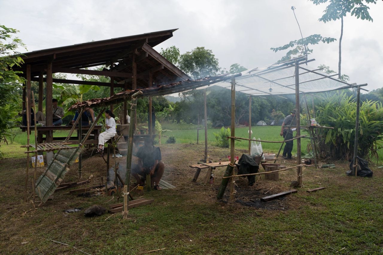 People gathering beside a handmade bamboo shelter and pavilion