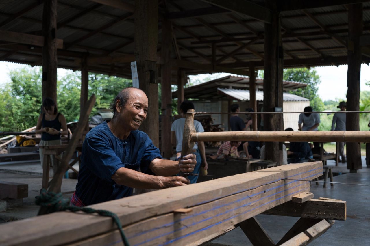 A craftsperson shaping a timber beam by hand