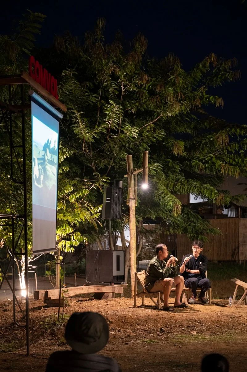 Speakers sharing an evening conversation beneath trees at Pham