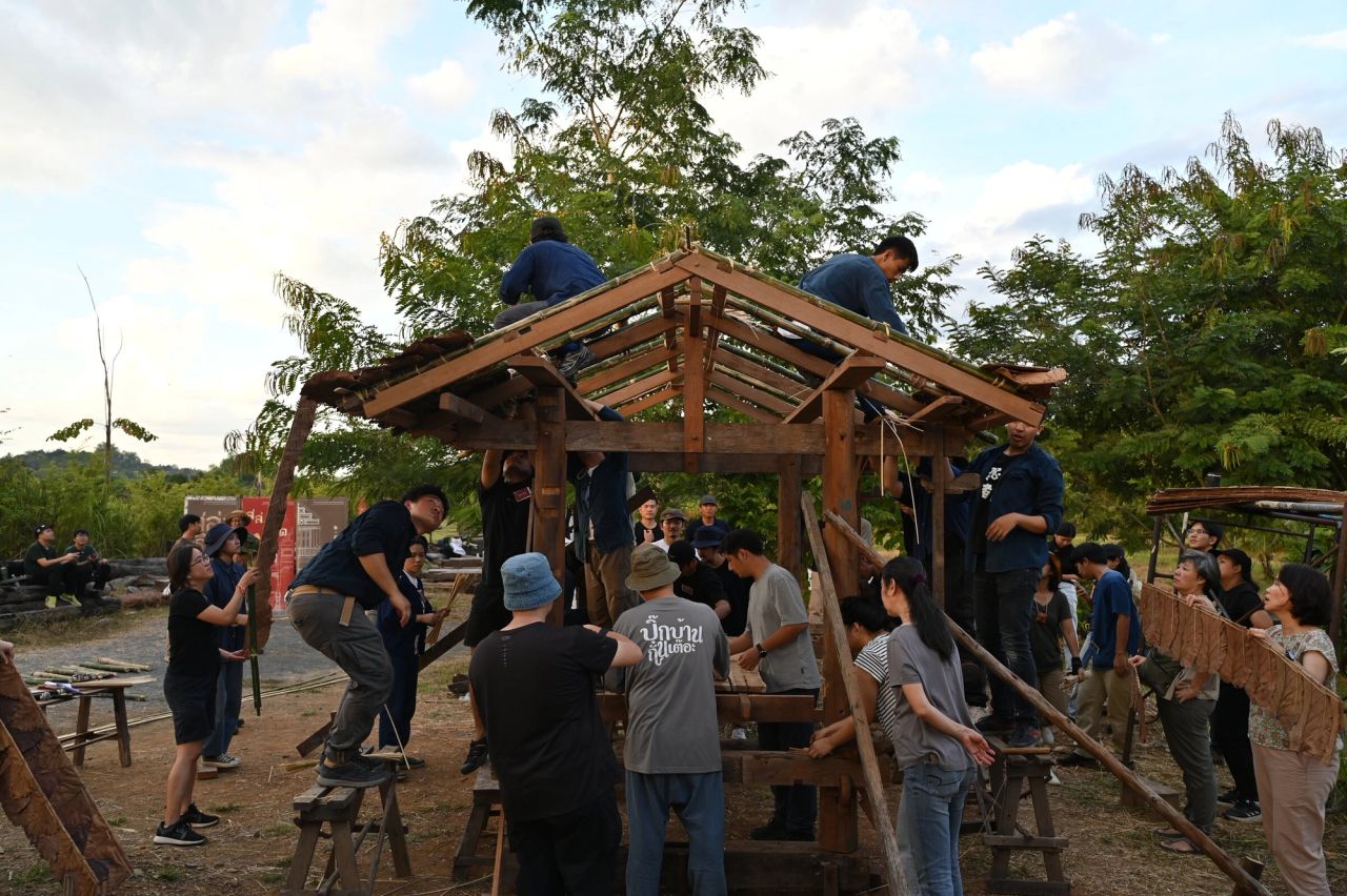 Participants raising the timber frame of a pavilion together
