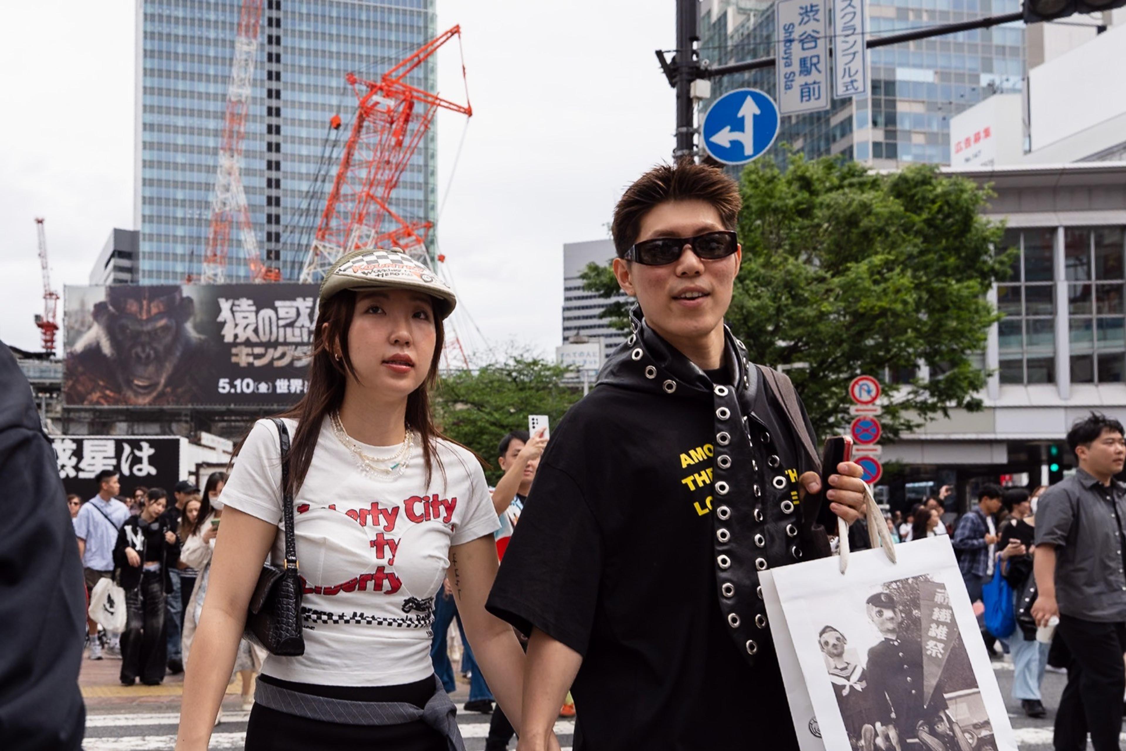 Stylish young couple crossing a busy city intersection with cranes and billboards behind