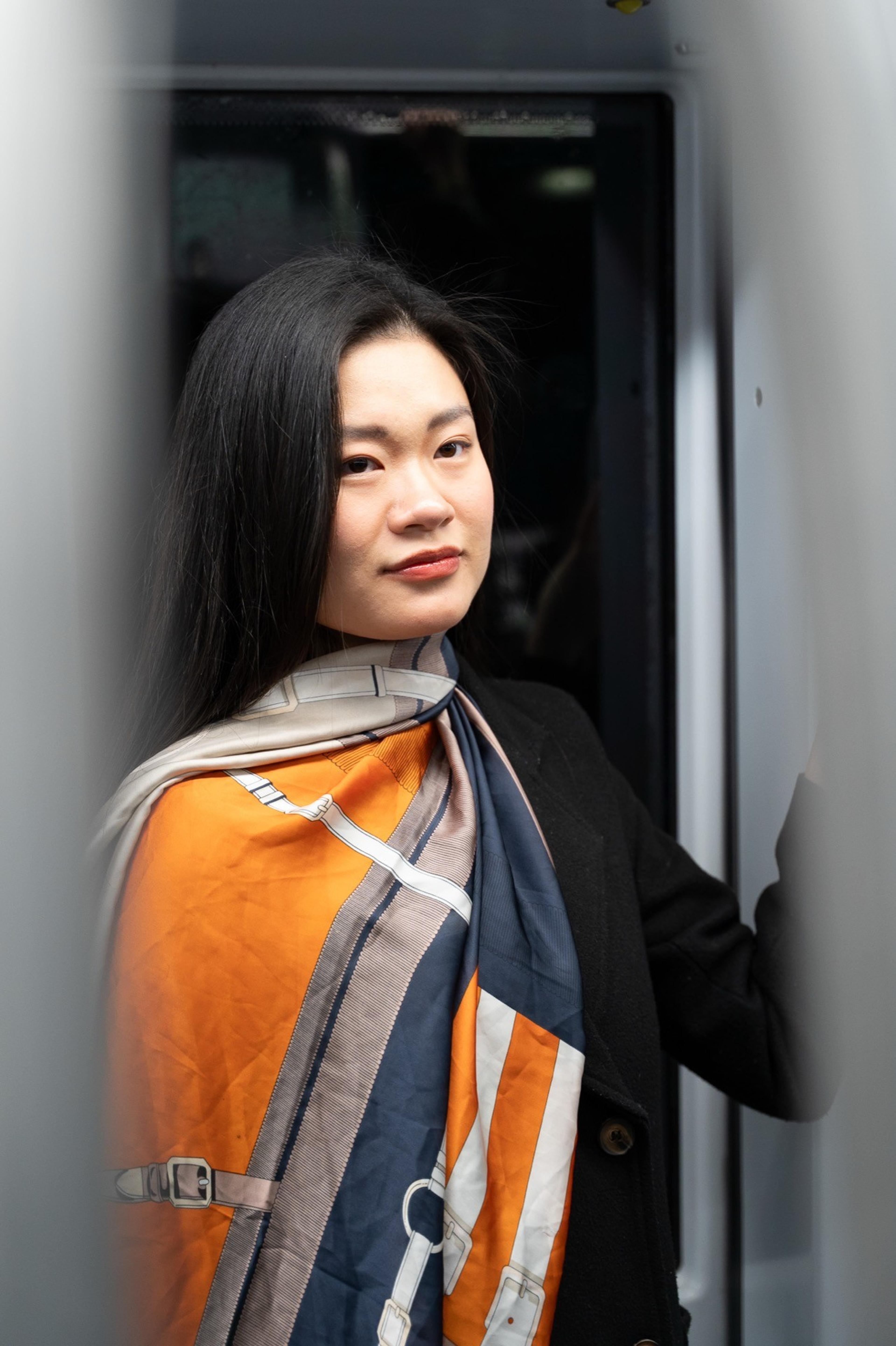 Portrait of a woman in an orange and navy scarf standing in the doorway of a train