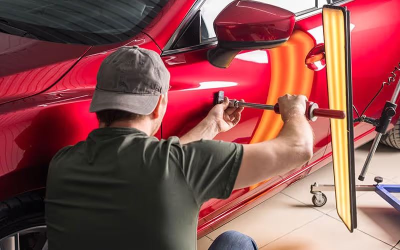 Paintless dent repair on a red car door