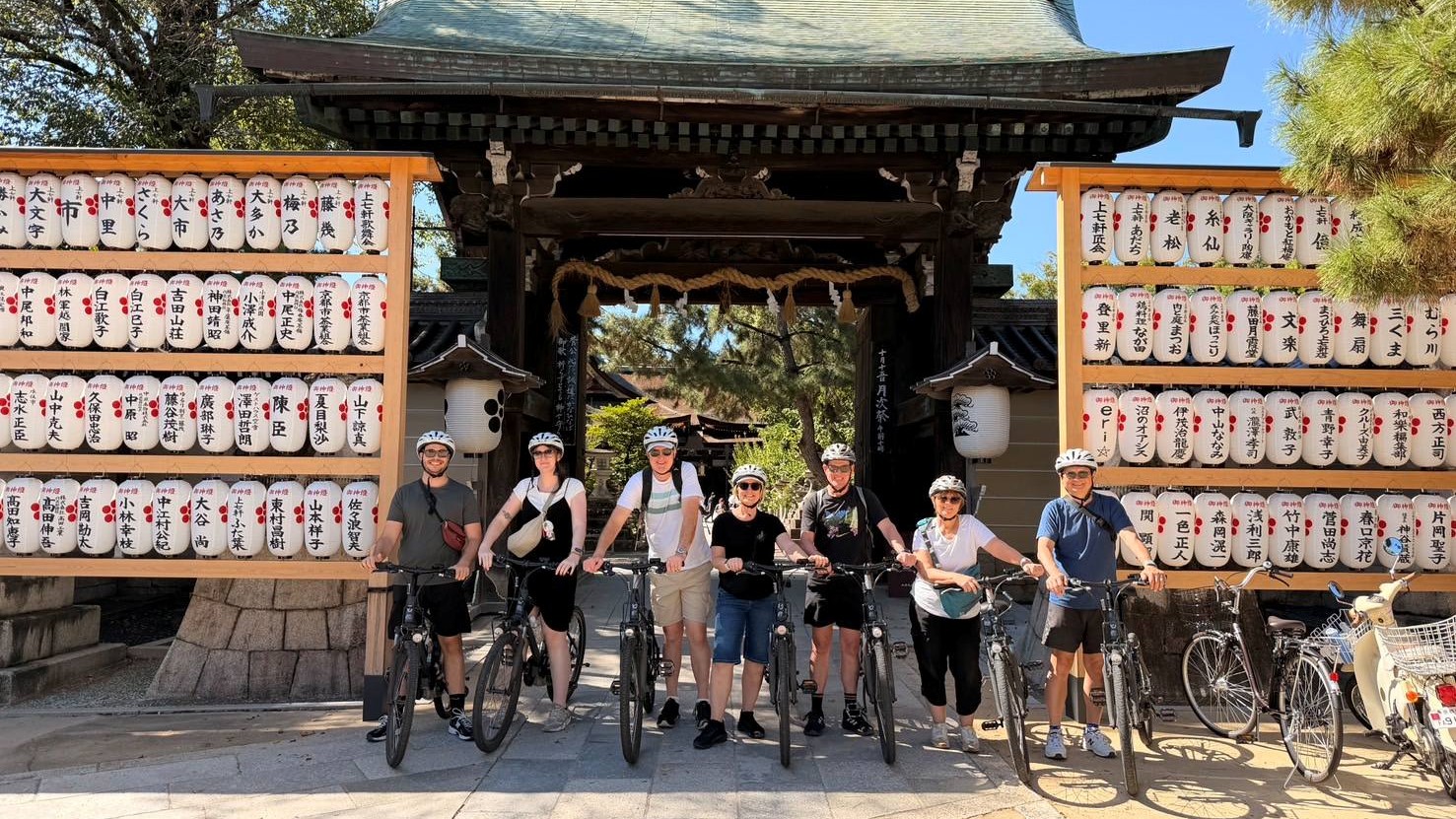 Small group, big discoveries: NORU riders explore Kitano Tenmangu Shrine, where traditional paper lanterns frame a gate most visitors never see.