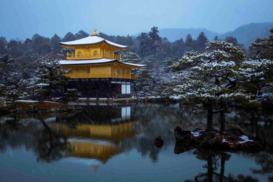 Kinkaku-ji Golden Pavilion temple covered in snow with perfect reflection in pond during winter in Kyoto
