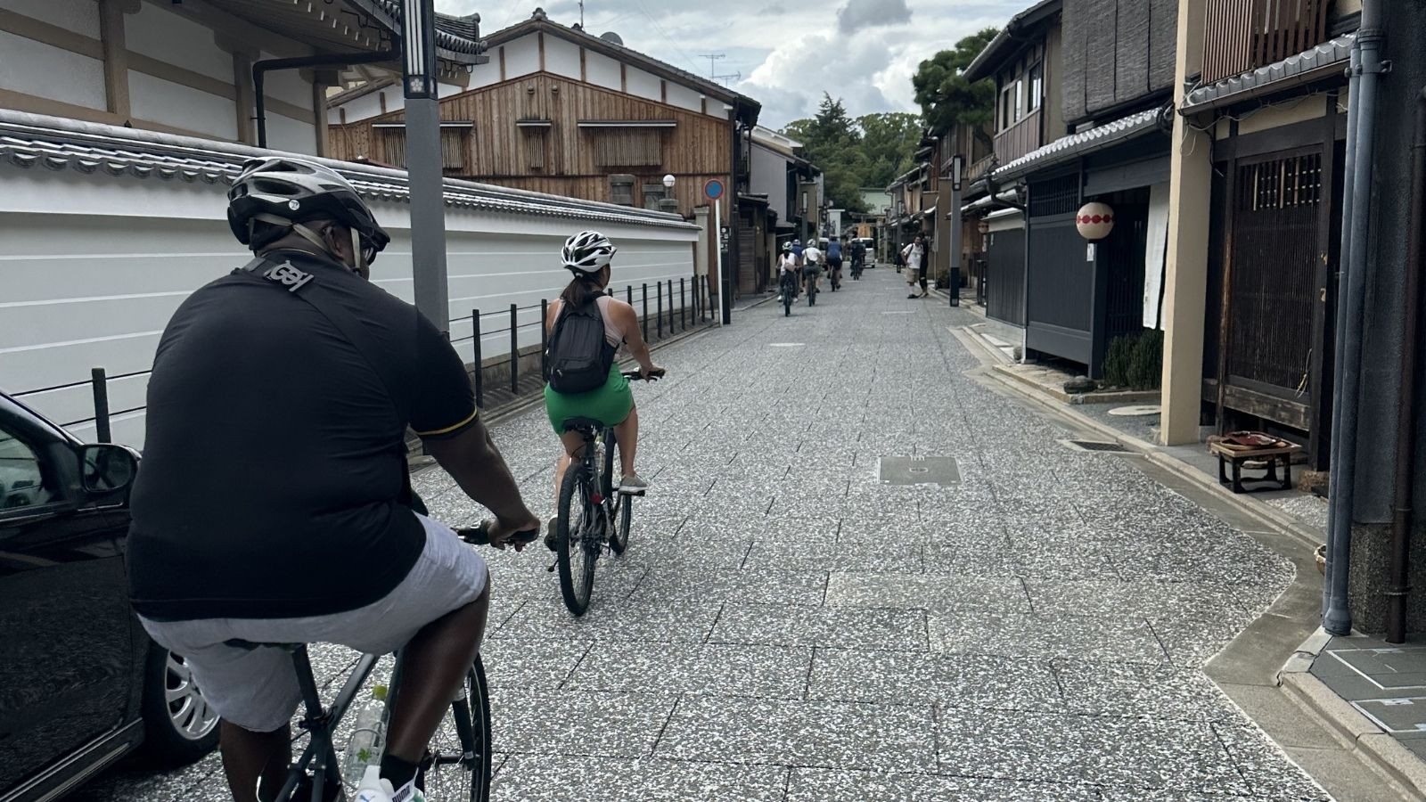A small group riding through one of Kyoto's older backstreets. Helmets on, single file, keeping left. These are the basics that matter most under Japan's new cycling rules.