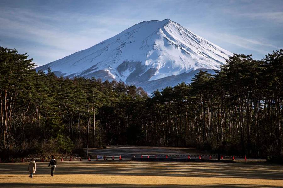 Two children walk towards a forest at the foot of Mount Fuji in Yamanashi Prefecture, Japan.