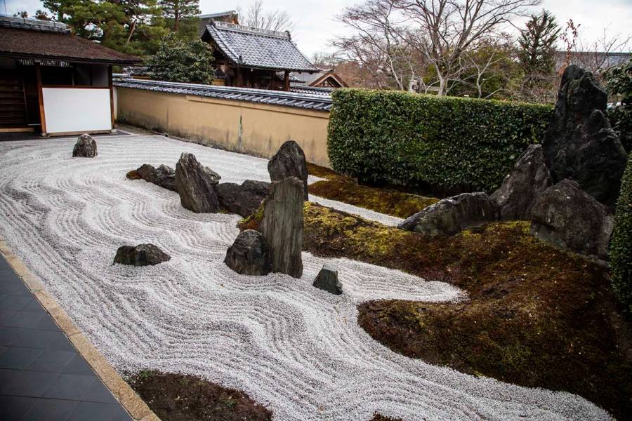 A zen rock garden in northern Kyoto, with raked white gravel, vertical stones, and moss-edged borders.