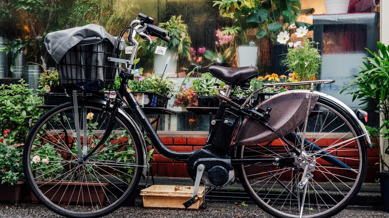 A typical Japanese 電動アシスト自転車 parked outside a Japanese flower shop. The motor unit is visible at the bottom bracket.