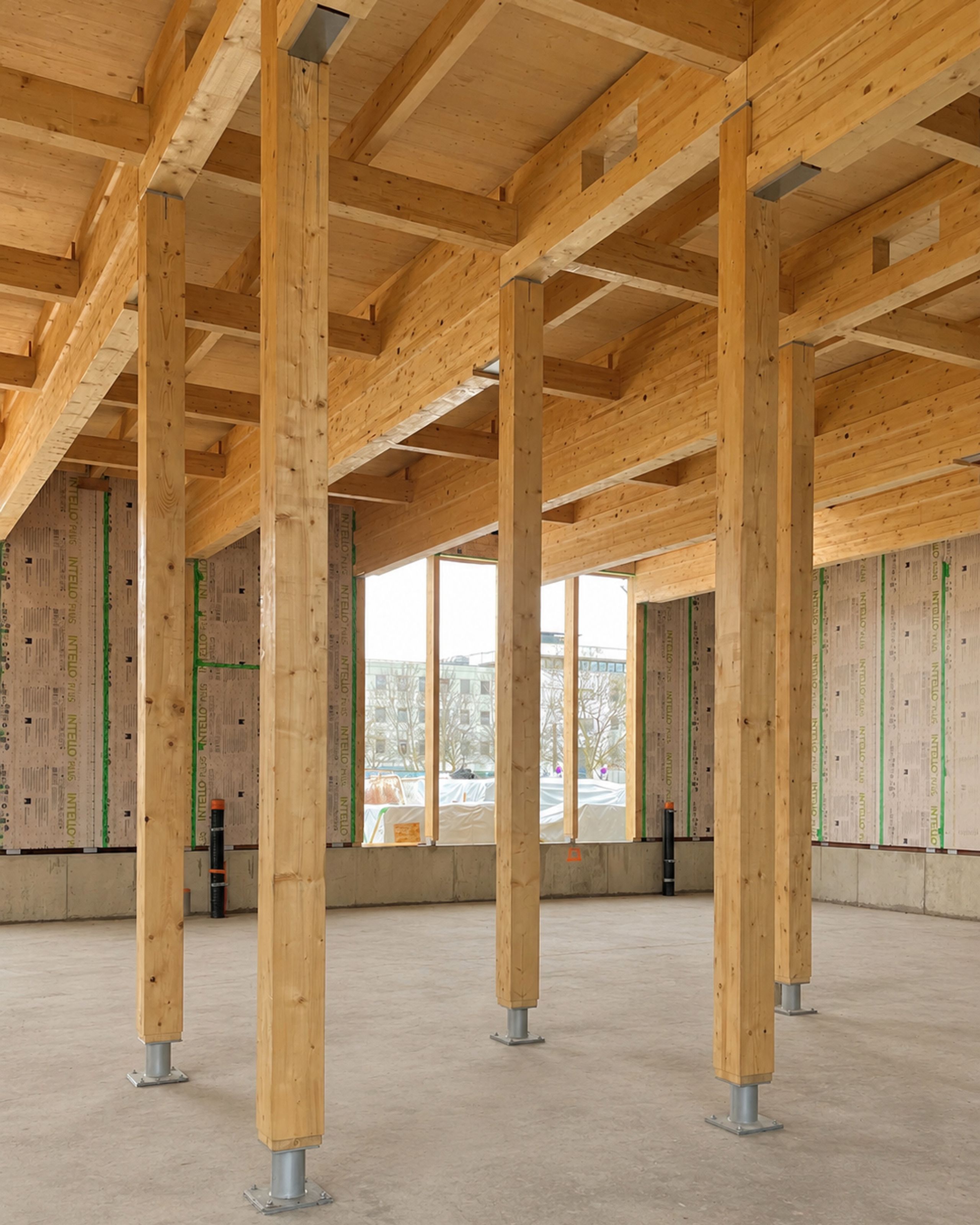 Structure bois apparente de la Cité campus Assia Djebar à Vaulx-en-Velin, poteaux et poutres lamellé-collé sur dalle brute, façade vitrée en fond de scène.
