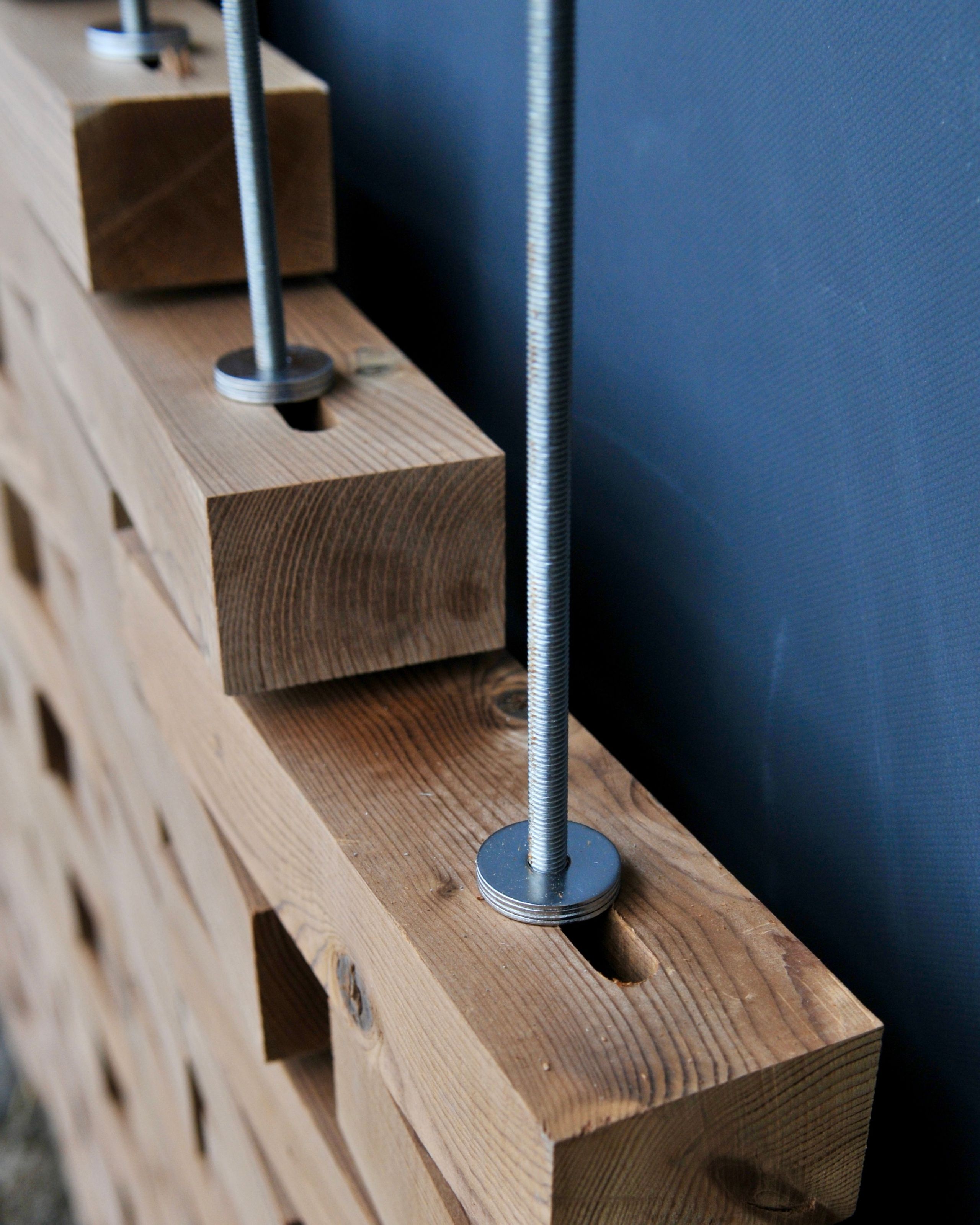 Détail constructif de la Maison de l’environnement à Hénin-Beaumont : empilement de briques de bois maintenues par tiges filetées et rondelles métalliques.