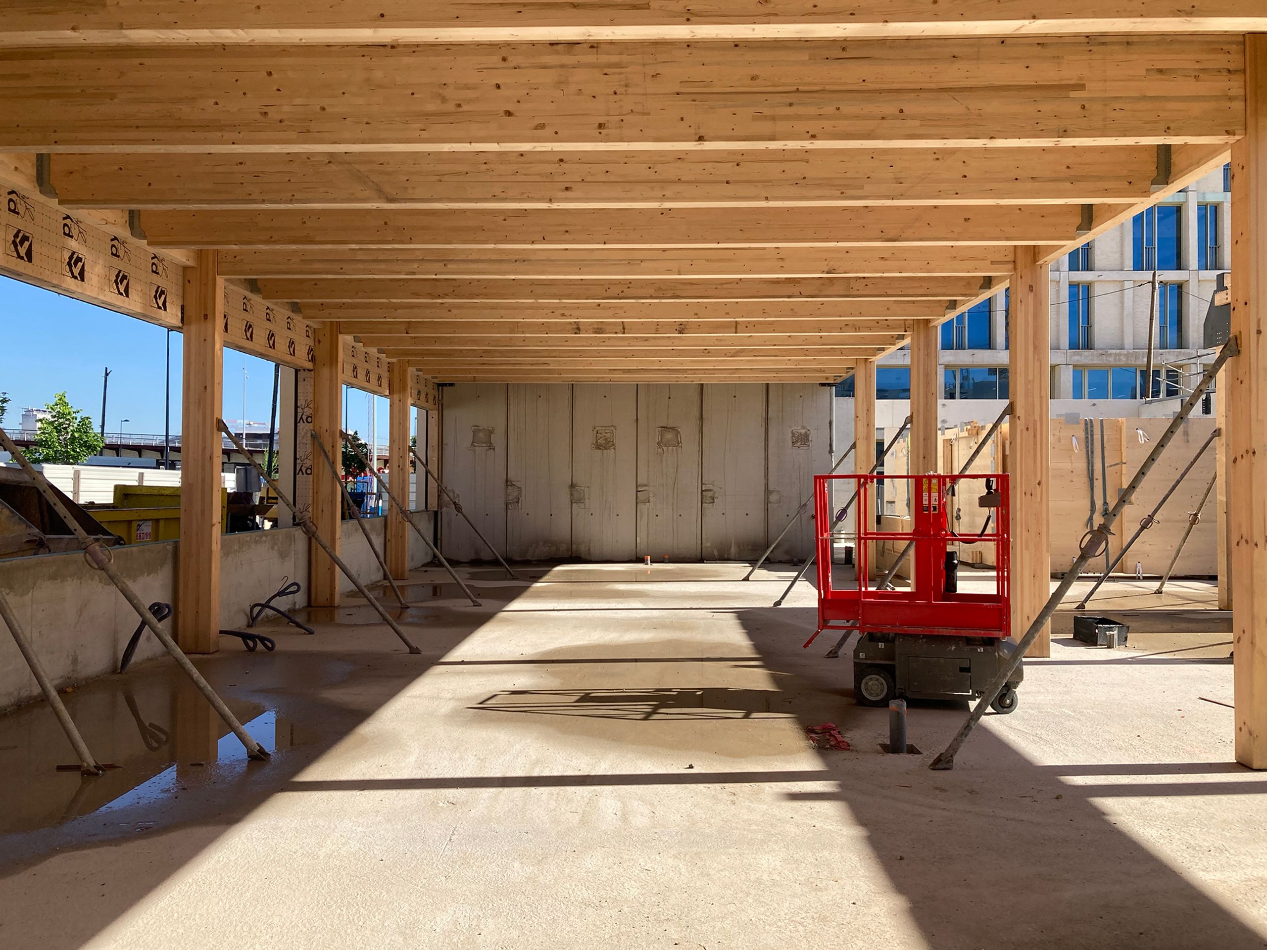Structure bois en cours de montage pour le groupe scolaire Frida Kahlo à Bordeaux, ossature poteaux-poutres préfabriquée sur dalle béton ouverte sur le parc.