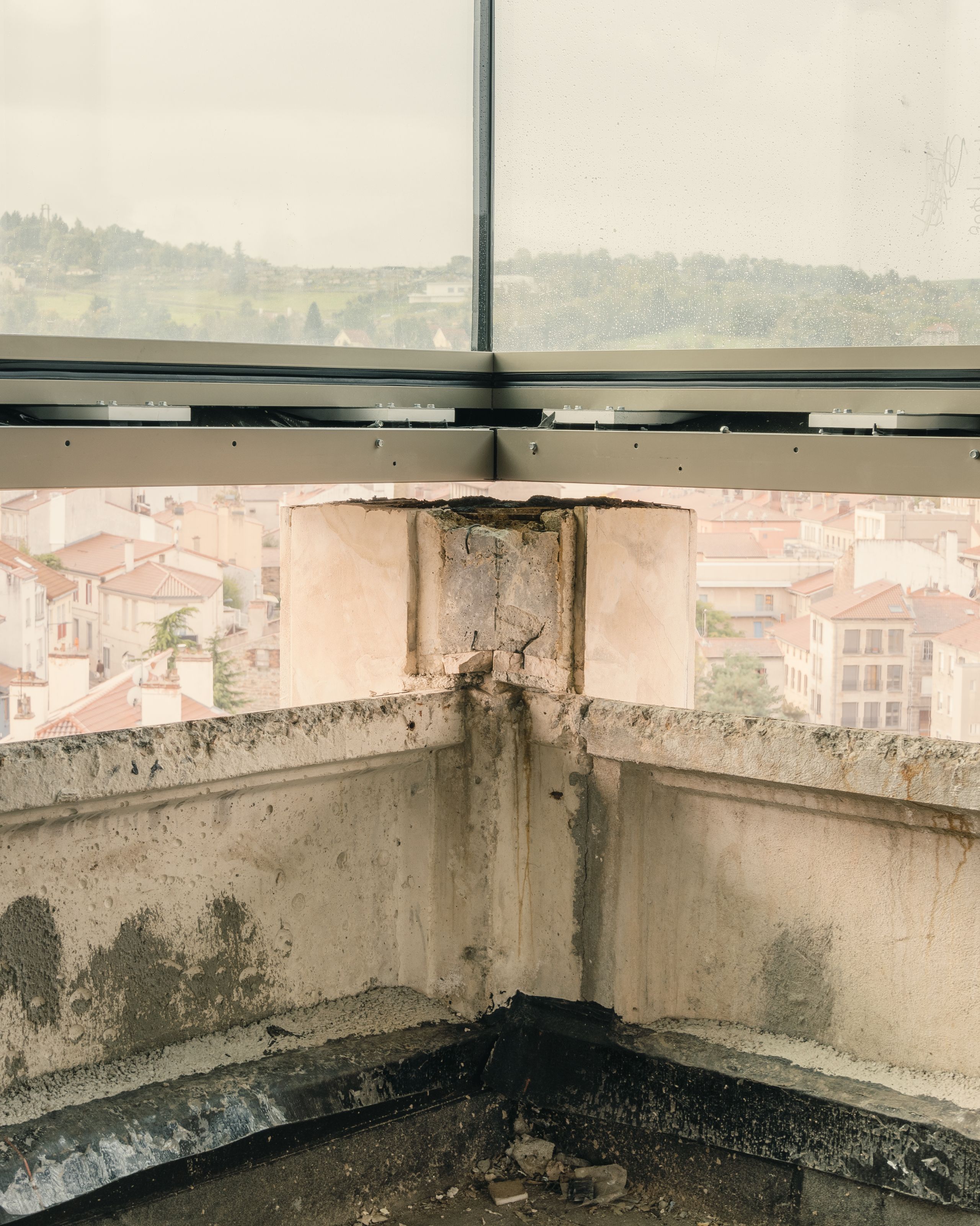 Angle de façade en béton brut en cours de curage, sous une nouvelle menuiserie vitrée panoramique, dans la tour IGH Émile Loubet en réhabilitation à Saint-Étienne.
