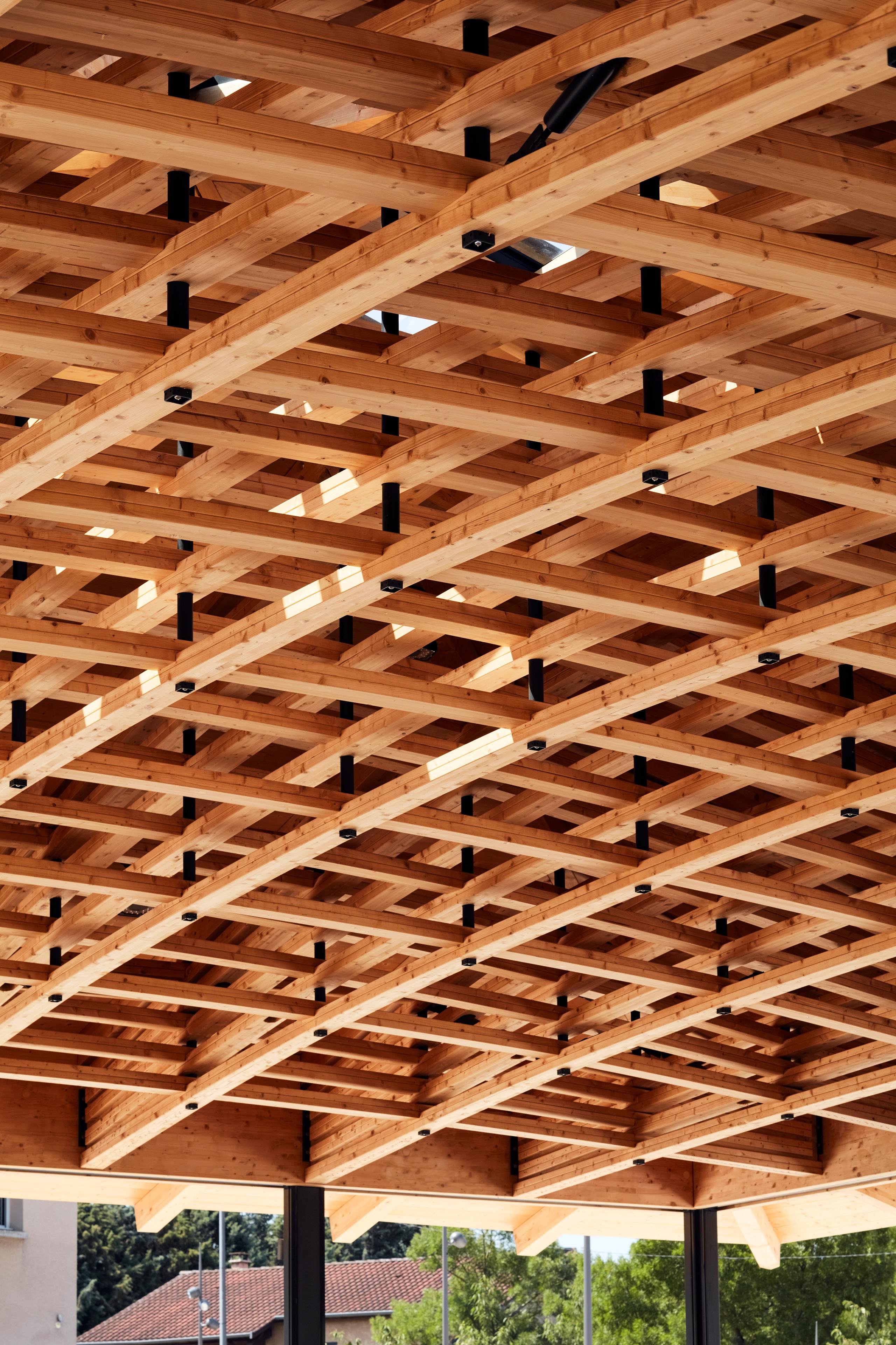 Charpente en lamellé-collé de la halle de marché de Marcy-l’Étoile, tissage tridimensionnel bois-métal formant une toiture carrée à quatre pans.