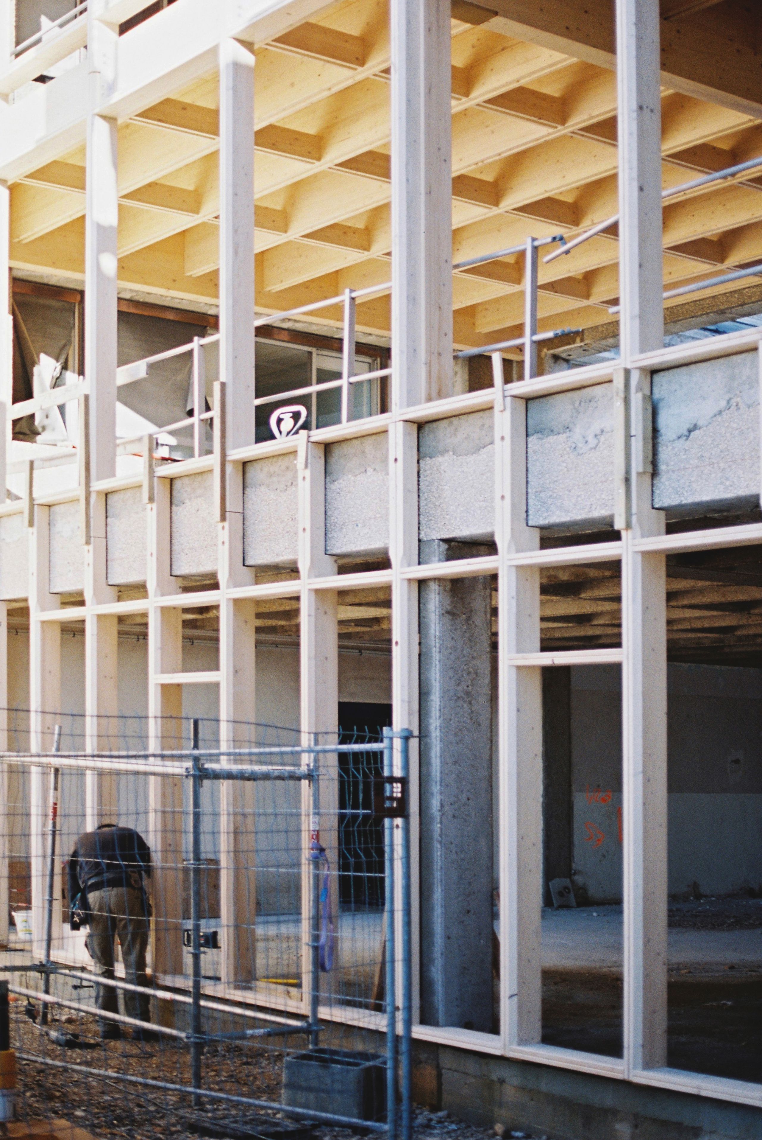 Chantier de restructuration du collège Maryse Bastié à Dole, montrant la trame bois rapportée sur la structure béton existante et les nouveaux planchers caissonés.