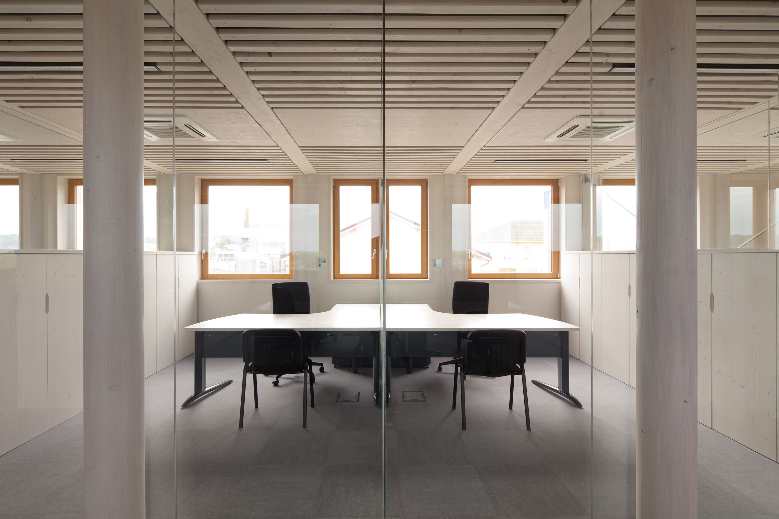 Plateau de bureaux rénové à Saint-Martin-Belle-Roche, cloisonné en verre, structure et mobilier bois clair, fenêtres bois et plafond à lames apparentes.