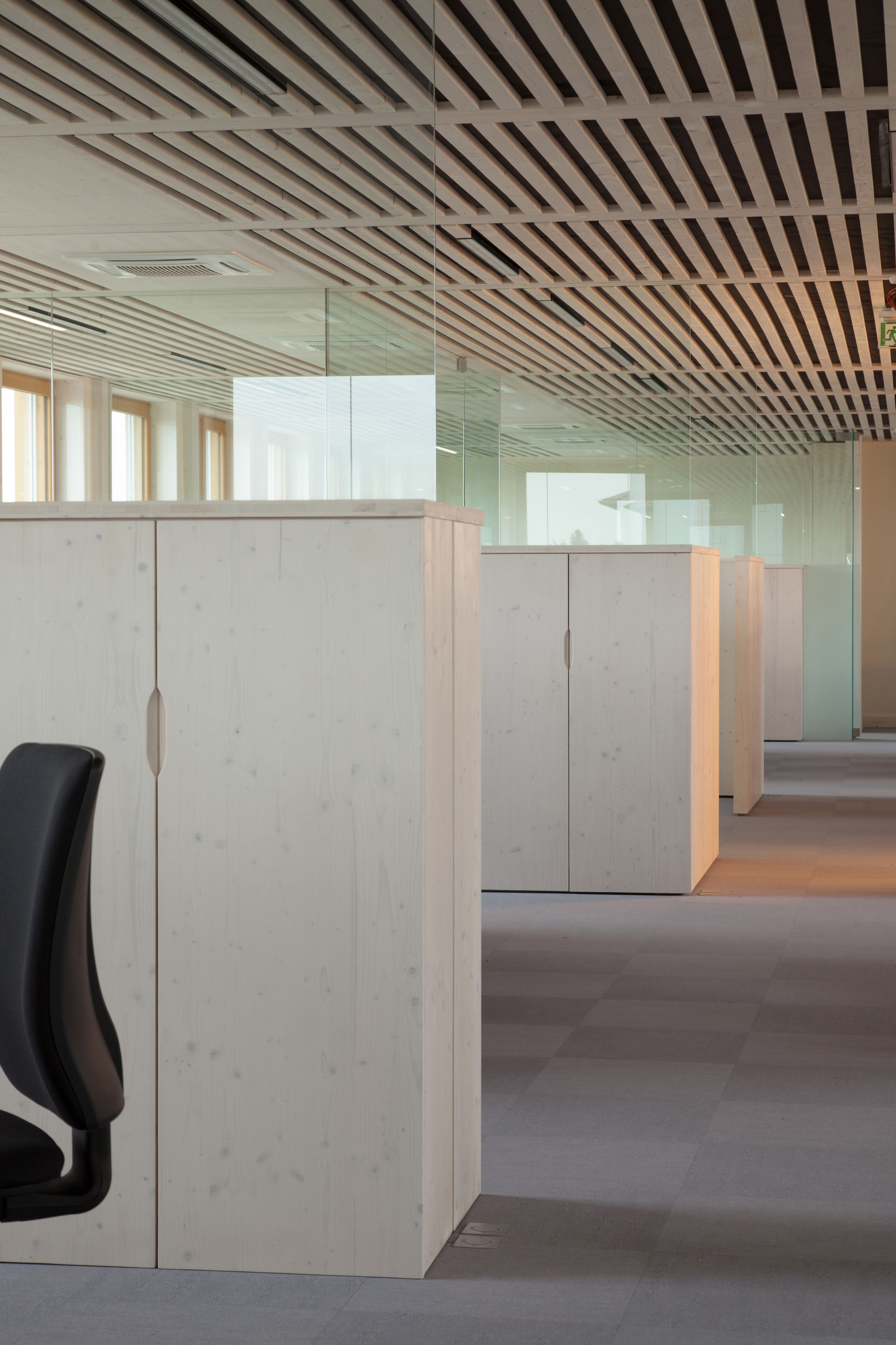 Plateau tertiaire rénové à Saint-Martin-Belle-Roche, mobilier en bois clair, cloisonnements vitrés et plafond à lames bois soulignant la trame structurelle.