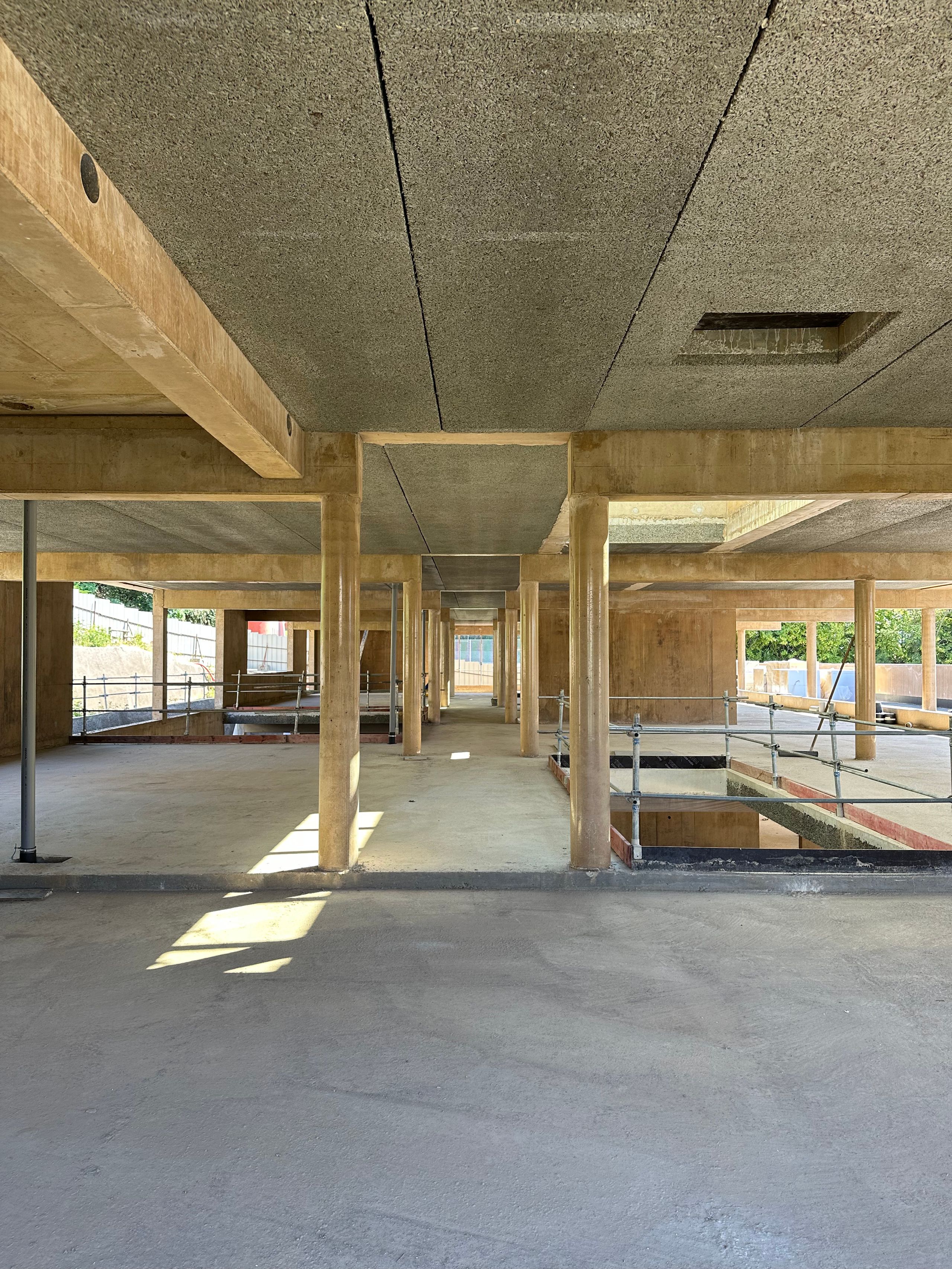 Plateau structurel de la Maison des familles à Limonest : plan libre en béton teinté, dalles en béton de bois, trame régulière de poteaux et vides en double hauteur.