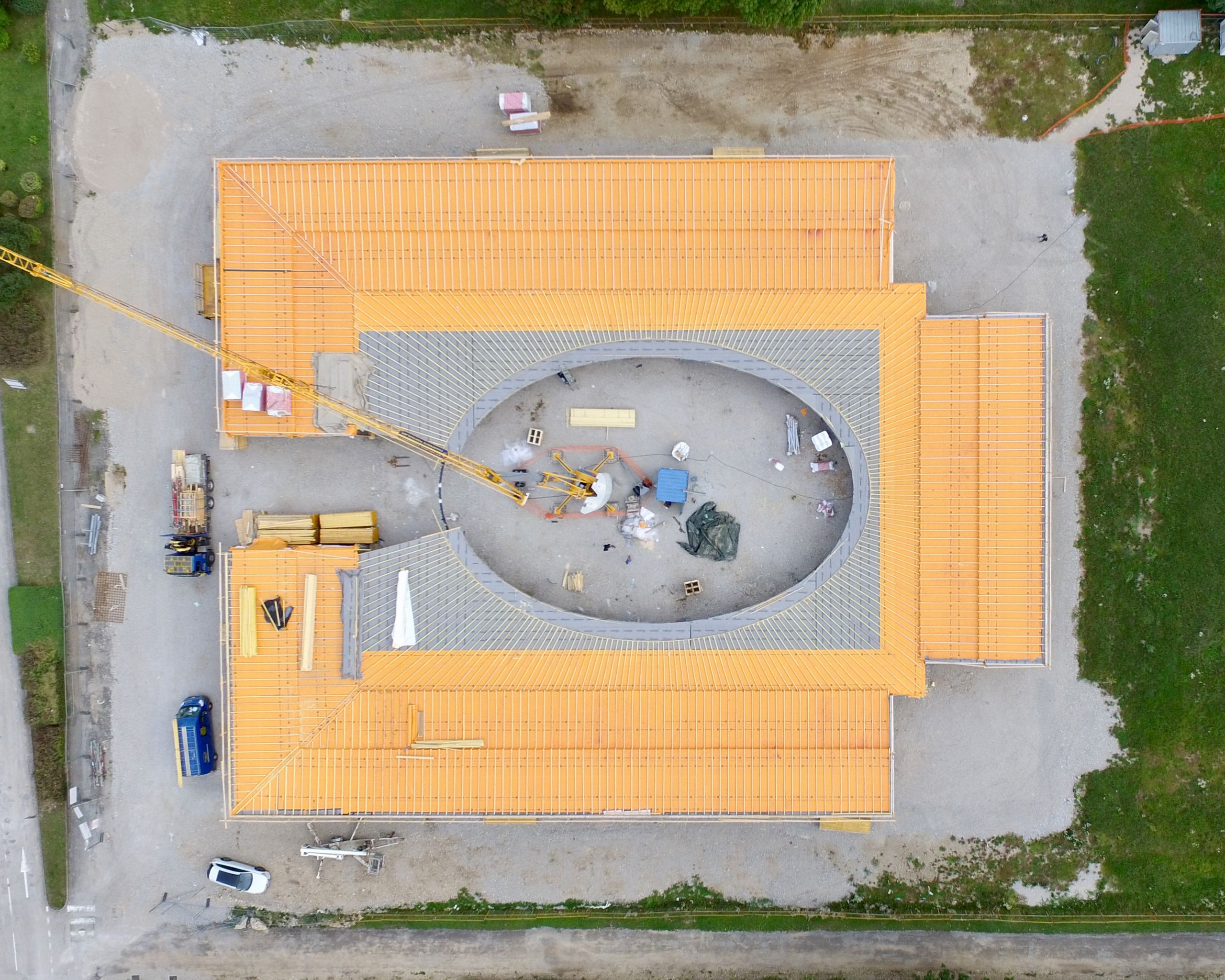 Vue aérienne du chantier de l’école élémentaire Hubert Reeves à Champagnole, toiture elliptique en impluvium entourant la cour centrale, structure bois en cours de pose.