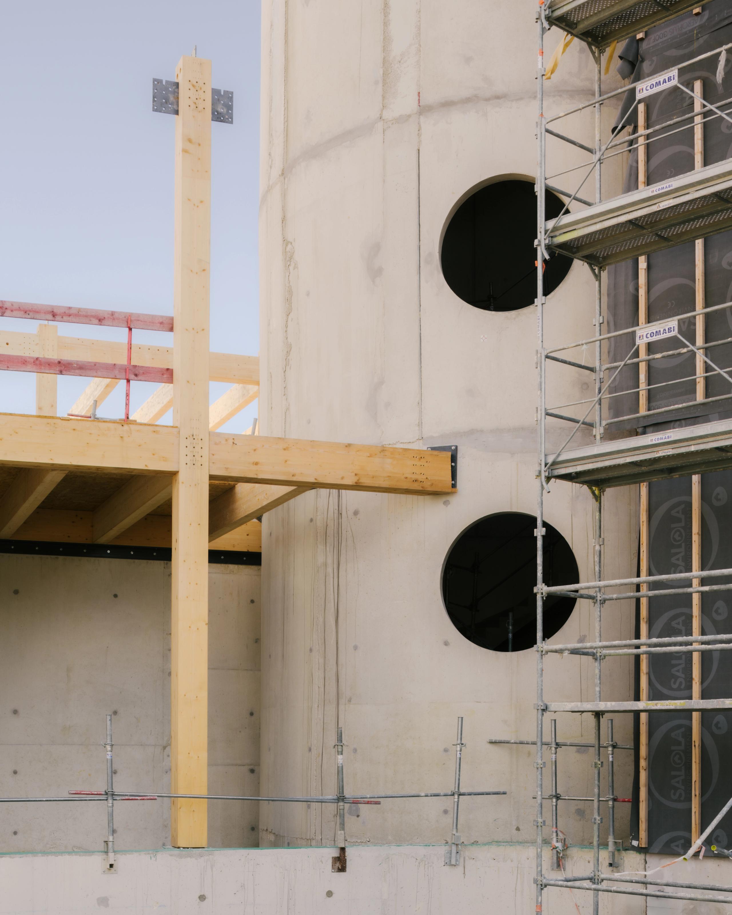 Chantier du groupe scolaire Dominique Frelaut à Colombes : structure mixte béton/bois, façade cour en cours de montage avec percements circulaires et échafaudages.