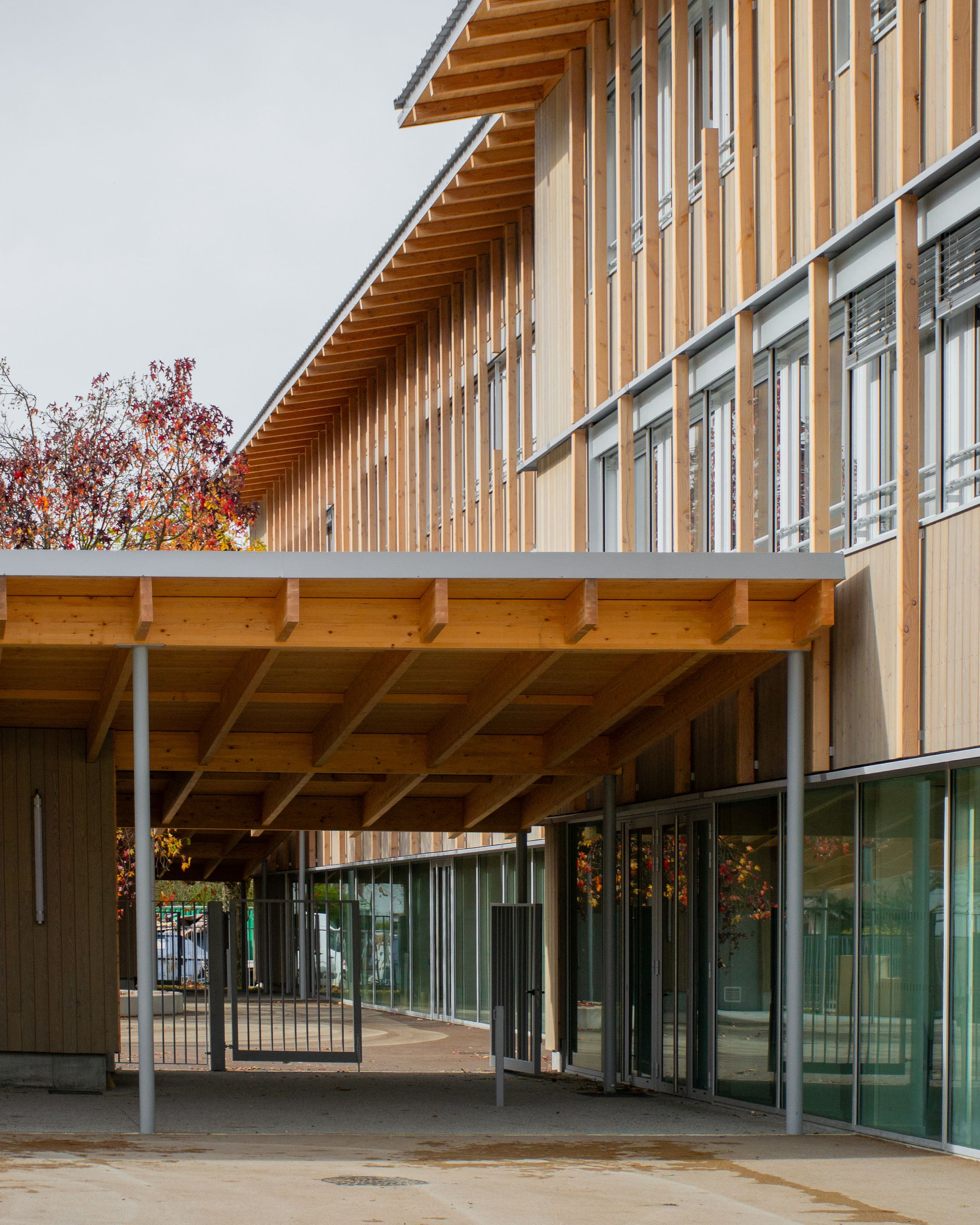 Transformation du groupe scolaire du Bouchet à Bonneville : surélévation-extension en ossature bois, préau couvert et façades vitrées continues sur cour.