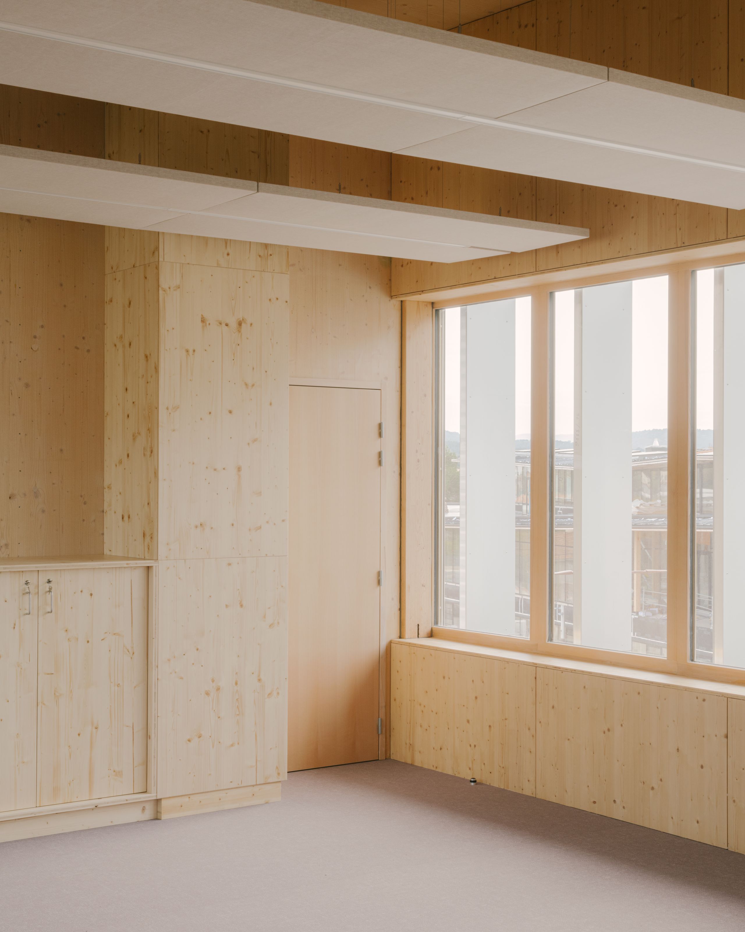 Intérieur en structure bois de la médiathèque et School complex Claudie Haigneré aux Pennes-Mirabeau, avec parois vitrées et plafonds acoustiques.