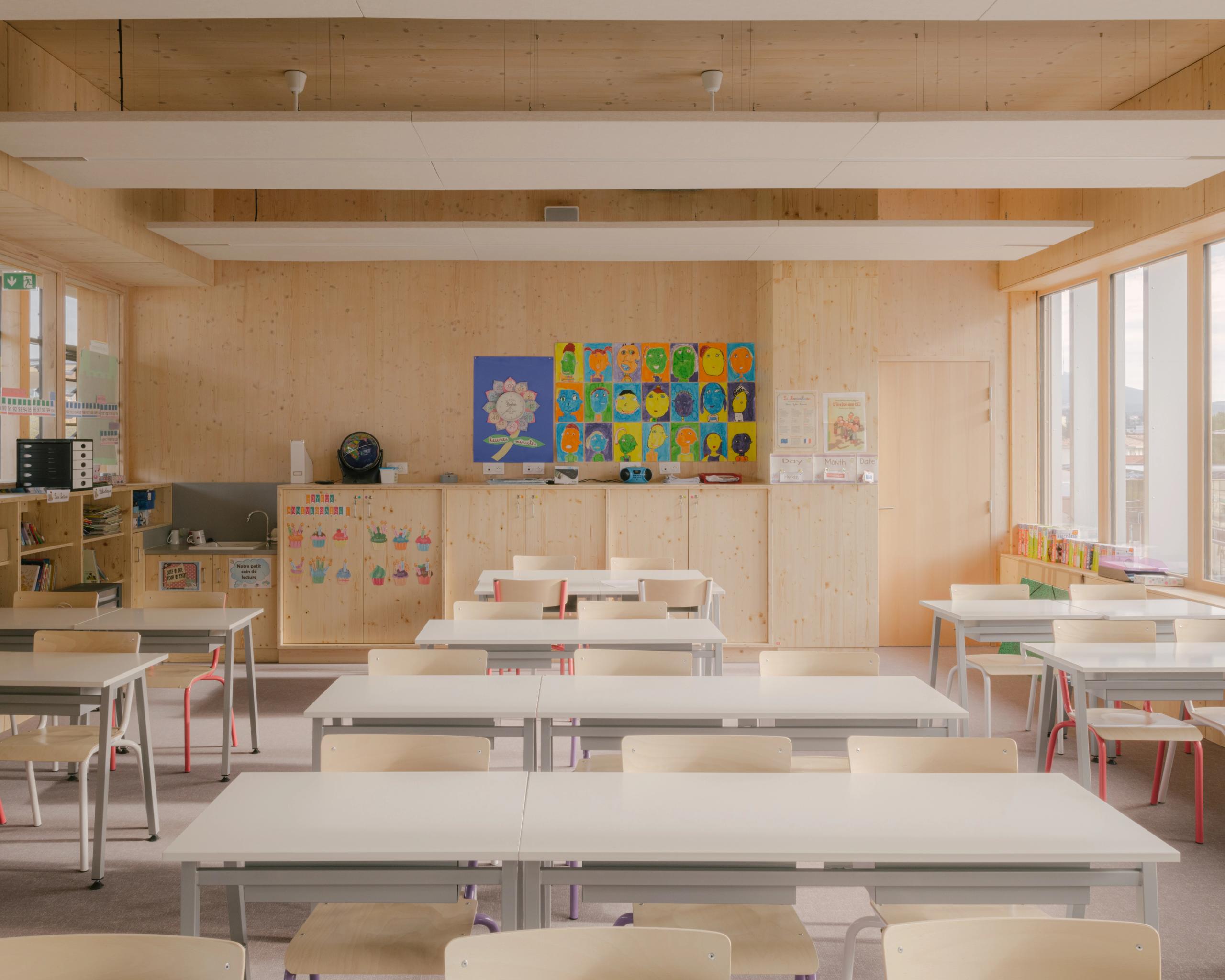 Salle de classe du School complex Claudie Haigneré aux Pennes-Mirabeau, structure bois apparente, lumière naturelle latérale et mobilier clair modulable.