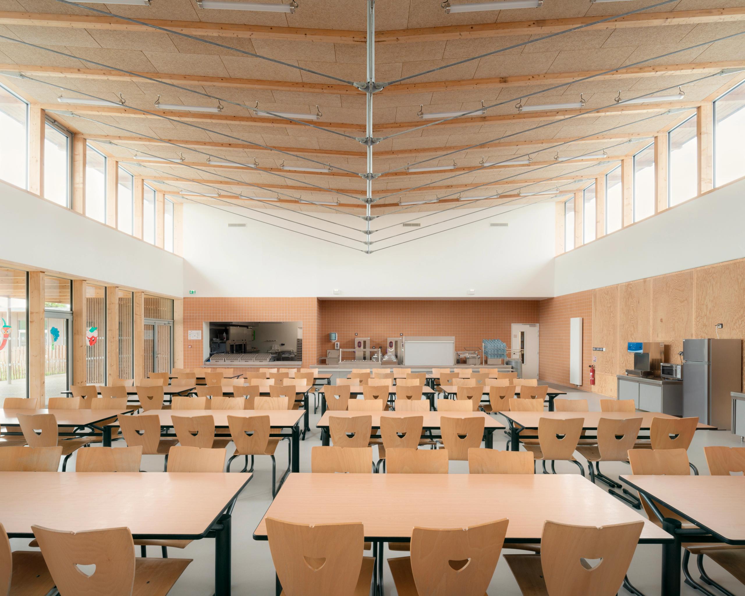 Cafeteria des groupes scolaires Jacqueline Auriol et Jean Jaurès au Bourget, vaste volume bois lumineux, charpente apparente et grandes baies en bandeau.