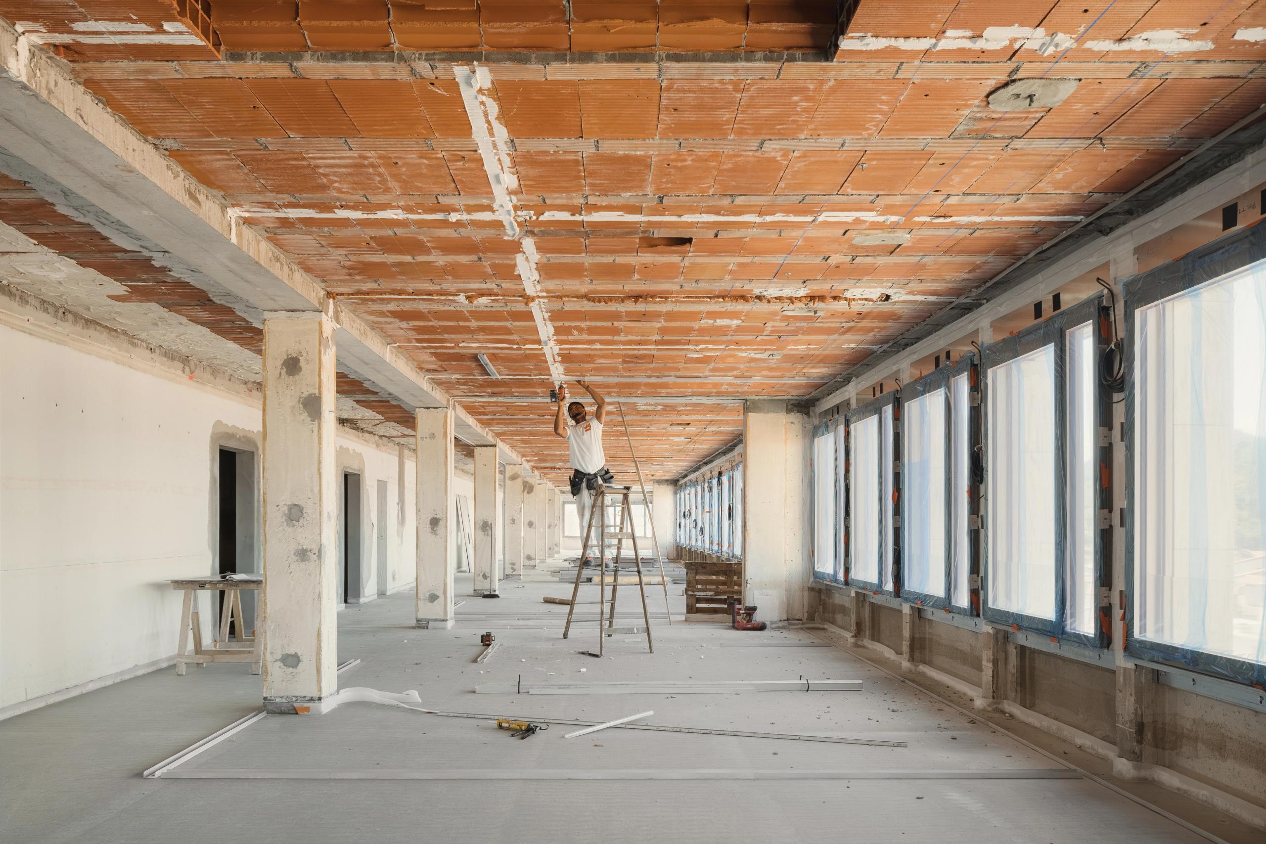 Plateau en curage de l’ancien IGH Émile Loubet à Saint-Étienne, structure poteaux-dalles apparente, grandes baies protégées et intervention au plafond.