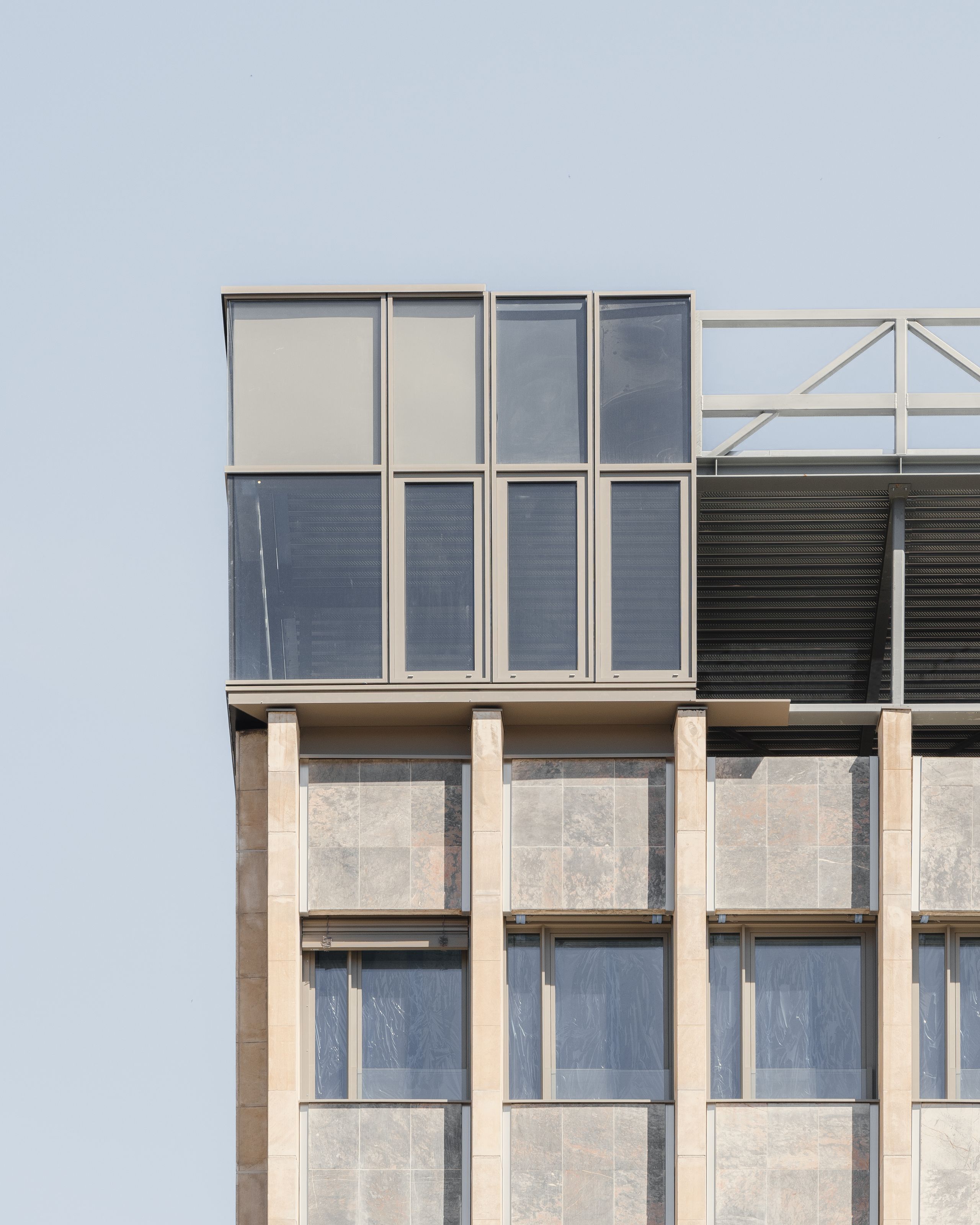 Façade réhabilitée de l’IGH Émile Loubet à Saint-Étienne, alternant trame béton-pierre et attique vitré métallique, montrant la nouvelle surélévation.