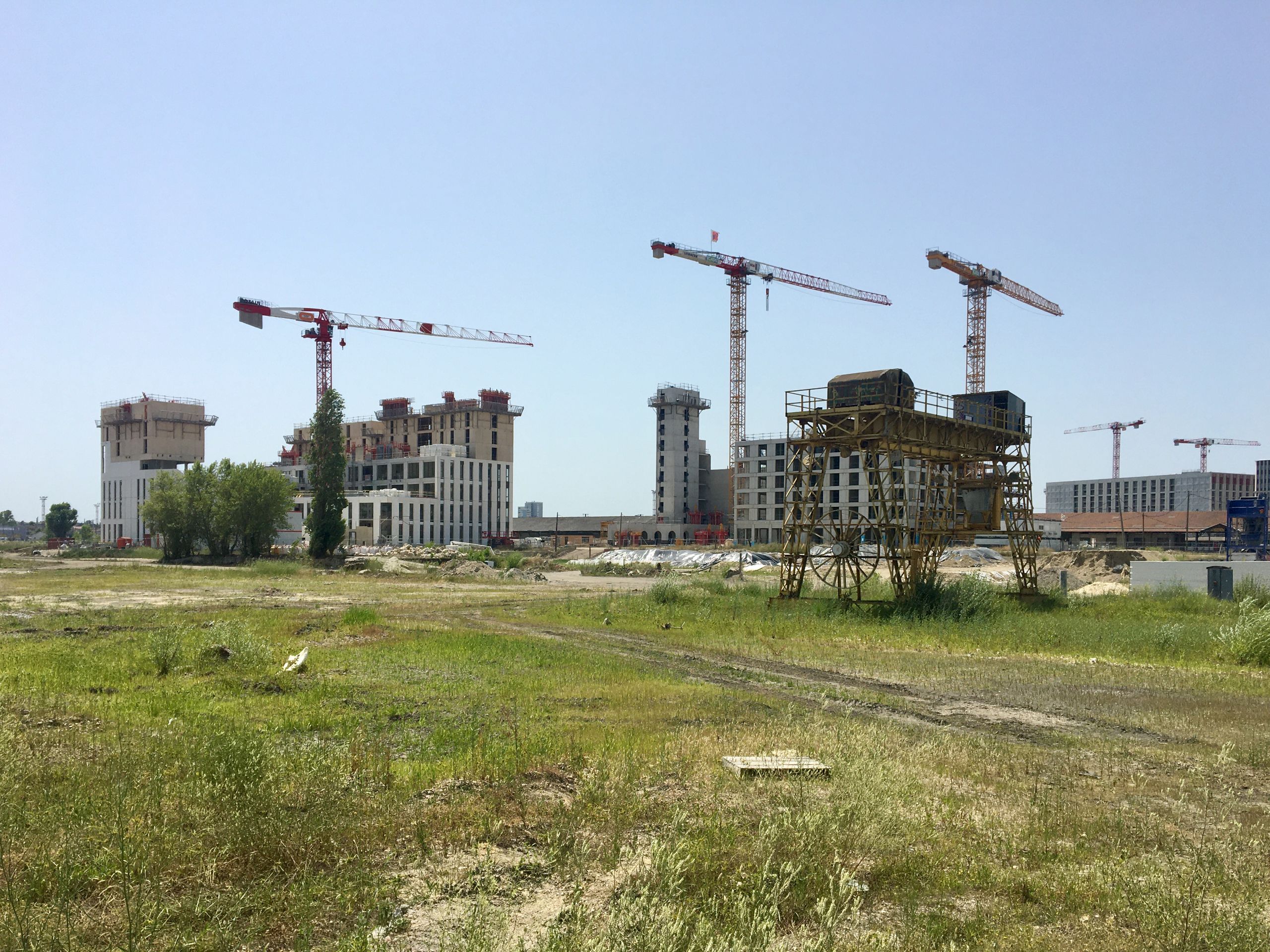 Construction site of the Mixed-Use Blocks in Bordeaux, with concrete frames, tower cranes and open ground foreground showing the urban redevelopment phase.