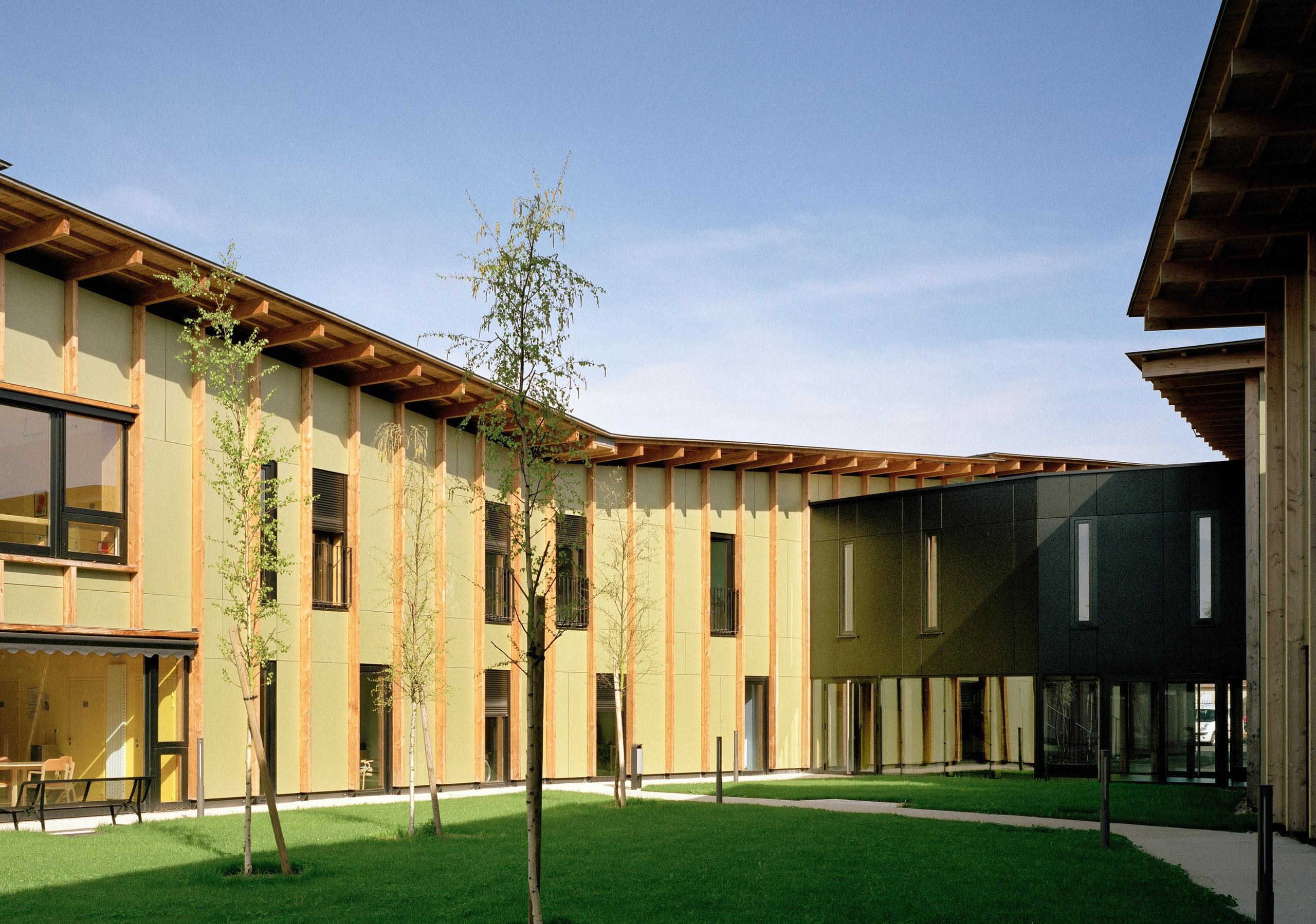 Façade bois et panneaux colorés de l’EHPAD de Mervans par Tectoniques, formant deux ailes autour d’un jardin clos, grandes baies vitrées sur les espaces de vie.