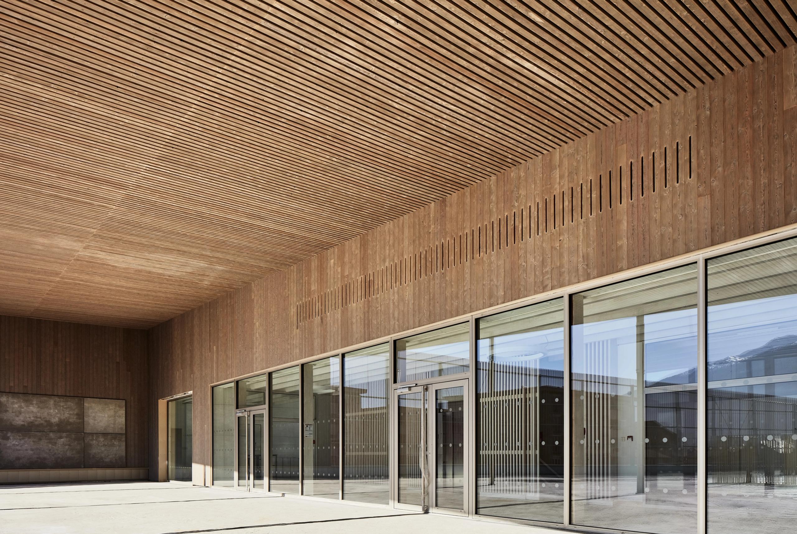 Façade en bois et grande marquise de la Maison de l’Enfance Simone Veil à Albertville, avec plafond à lames, percements verticaux et larges baies vitrées.