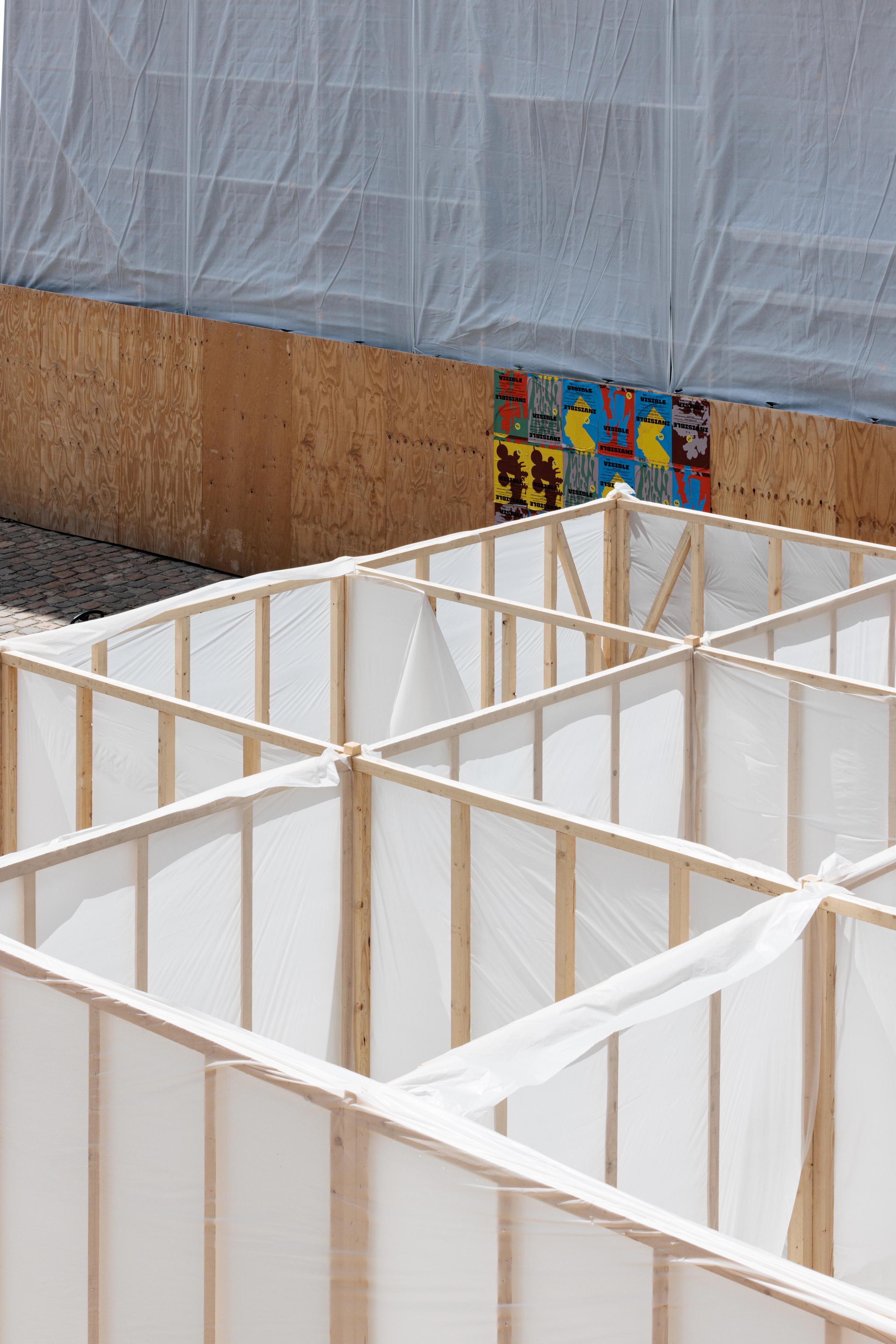 Workshop 60x60 à Versailles : structure labyrinthique en ossature bois et film plastique translucide, en dialogue avec les façades en chantier voisines.