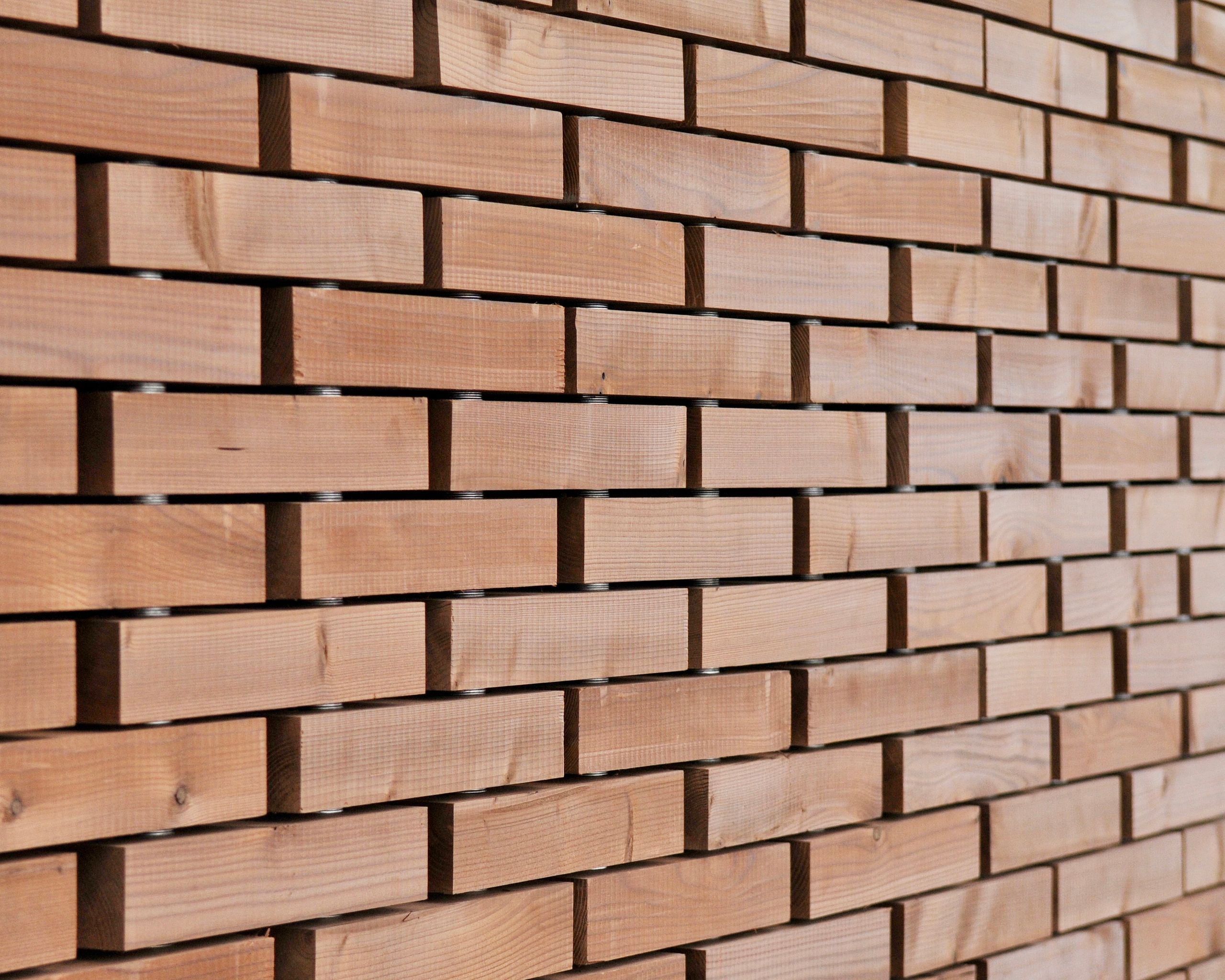 Détail de façade en briques de bois ajourées du Pavillon du Parc des Îles à Hénin-Beaumont, montrant l’assemblage modulaire en filière sèche.